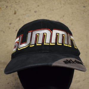 Könnte beinhalten: Schwarze und graue Baseballkappe mit dem Wort "Summit" in silbernen, roten und gelben Buchstaben gestickt. Die Kappe hat ein graues Schild mit dem Wort "ski-doo" in Schwarz gestickt.