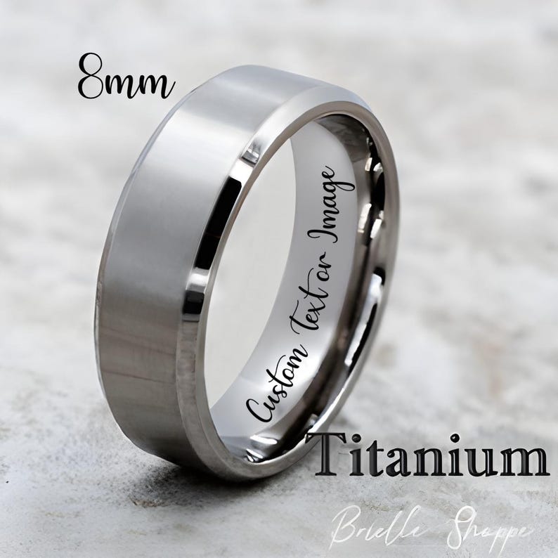 May include: A silver-colored titanium ring with a flat top and beveled edges. The ring is 8mm wide and features the text "Custom Text or Image" and "Titanium". The ring is a piece of jewelry.
