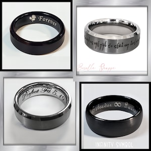 May include: Four rings with engraved text and designs. One black ring has "Forever" and a rose. Another has script. A third ring says "Perfect Fit 5.19". The last ring has "Salvador &infin; Laura" and "INFINITY SYMBOL".