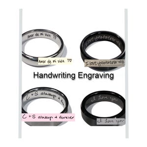 May include: Four rings with handwriting engraving options. Two silver rings and two black rings are displayed. The text on the rings includes phrases like "Amor de mi vida", "I love you forever", and "C + S always + forever". The image also includes the text "Handwriting Engraving".