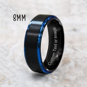 May include: Black tungsten carbide ring with a blue inlay and a beveled edge. The ring is 8mm wide and has the text "Custom Text or Image" engraved on the inside.