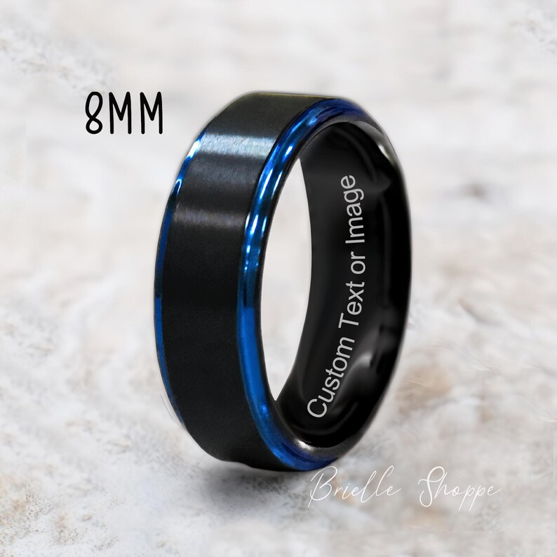 May include: Black tungsten carbide ring with a blue inlay and a beveled edge. The ring is 8mm wide and has the text "Custom Text or Image" engraved on the inside.