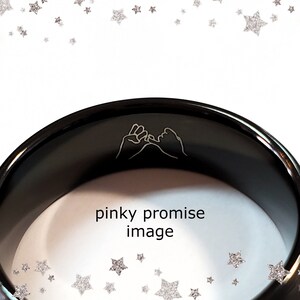 May include: Black ring with a pinky promise design engraved on the inside. The ring is made of a smooth, polished metal.