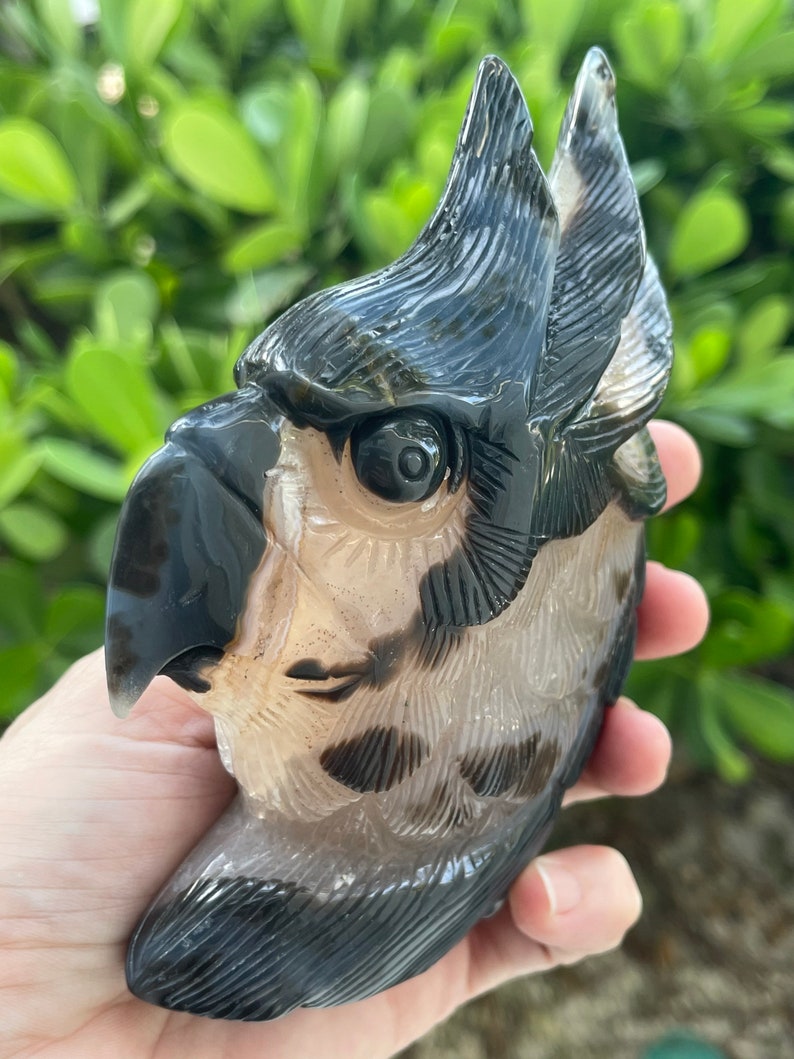 Pode incluir: Uma figura de coruja esculpida em &aacute;gata preta e branca. A coruja tem um rosto detalhado com um olho grande e um bico. A figura tem aproximadamente 12,5 cm de altura.