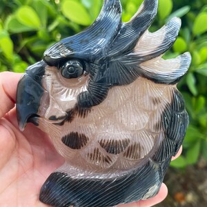 Pode incluir: Uma escultura de papagaio de &aacute;gata esculpida com faixas pretas e brancas. O papagaio tem uma cabe&ccedil;a e penas detalhadas.