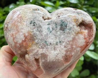 May include: A heart-shaped pink and white agate crystal with green inclusions. The crystal is polished and has a smooth surface.