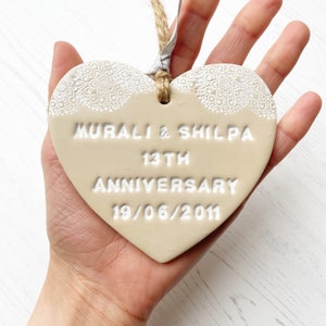 Personalised anniversary gift, beige clay heart with a white lace edge at the top of the heart with jute twine for hanging, the heart is personalised with MURALI & SHILPA 13TH ANNIVERSARY 19/06/2011