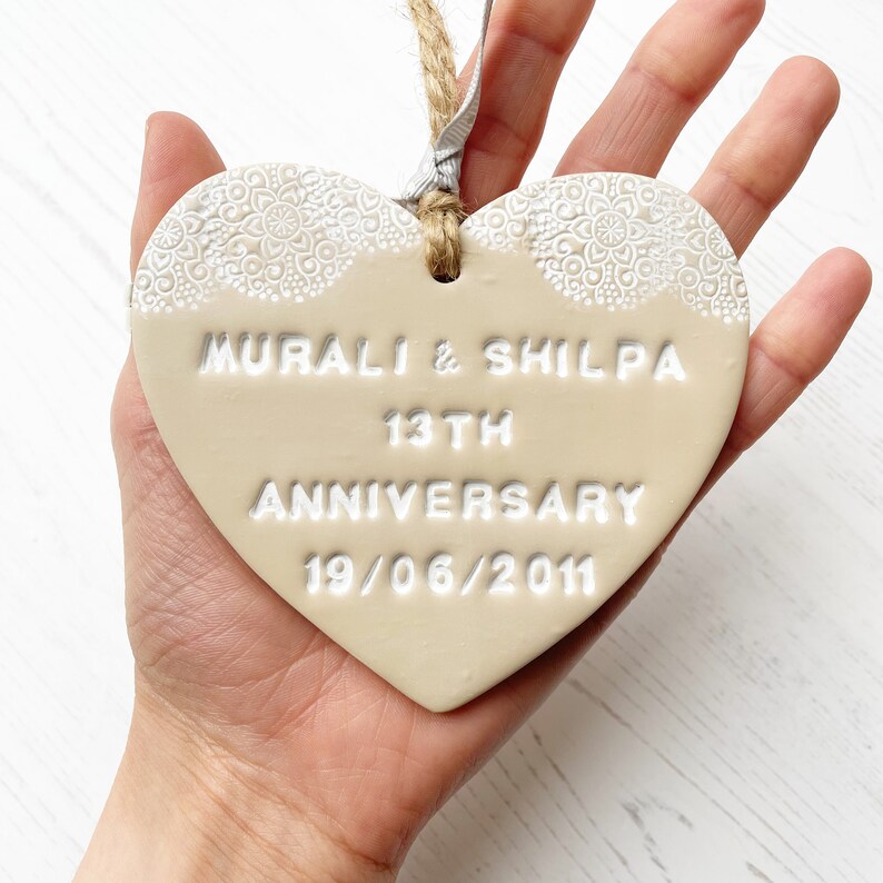 Personalised anniversary gift, beige clay heart with a white lace edge at the top of the heart with jute twine for hanging, the heart is personalised with MURALI & SHILPA 13TH ANNIVERSARY 19/06/2011