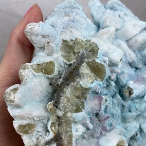 May include: A cluster of light blue, white, and green crystals. The crystals are arranged in a random pattern and have a rough, textured surface.