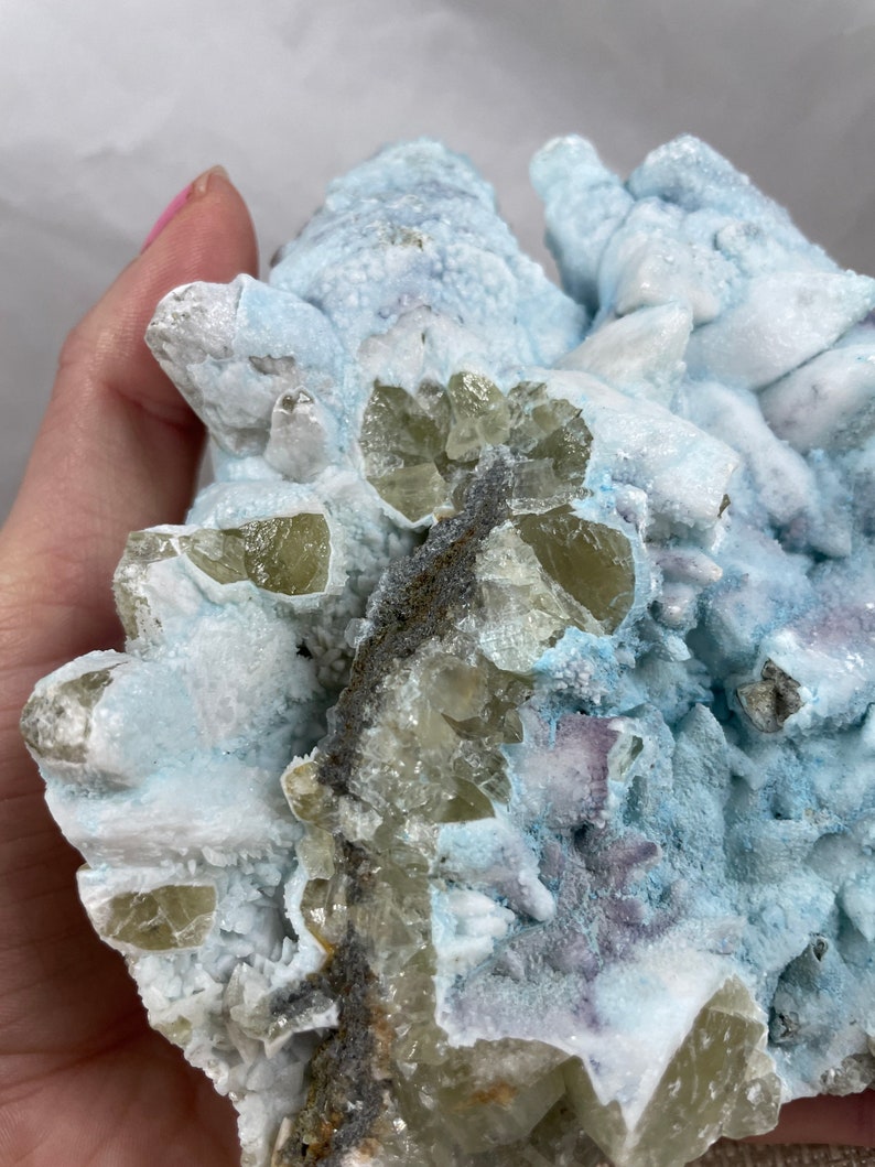 May include: A cluster of light blue, white, and green crystals. The crystals are arranged in a random pattern and have a rough, textured surface.