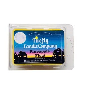May include: A yellow wax melt in a clear plastic container with a label that reads "Firefly Candle Company Pineapple Float handmade in Hilton Head Island South Carolina". The label has a night sky background with a moon, stars, and a firefly.