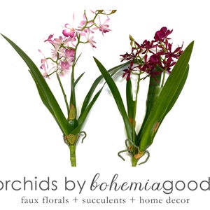 May include: Two artificial orchid plants with green leaves. The orchid on the left has pink flowers and the orchid on the right has purple flowers. The text "orchids by bohemia goods" and "faux florals + succulents + home decor" is below the orchids.
