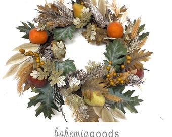 May include: A circular wreath featuring artificial green oak leaves, golden wheat stalks, orange fruit, yellow pears, and silver-toned pinecones. The text below reads: bohemiagoods, modern rustic + wedding supplies + florals.