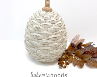 May include: A white woven pumpkin-shaped decorative object with a distressed finish and a brown stem, accompanied by a cluster of dried brown leaves and small pinecones. The text "bohemiagoods" and "modern rustic + wedding supplies + florals" appears.