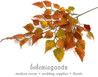 May include: A decorative branch featuring serrated, autumn-colored leaves in shades of orange, red, yellow, and green. The branch has a thin, dark brown stem that splits into multiple smaller twigs, each adorned with variegated foliage.