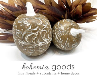 May include: Two decorative gourds with a white floral design. The gourds are a light brown color and have a rustic, farmhouse style.