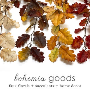 May include: A garland of faux oak leaves in various shades of fall colors, including cream, yellow, orange, and red. The garland is perfect for adding a touch of autumn to your home decor.