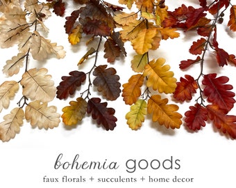 May include: A garland of faux oak leaves in various shades of fall colors, including cream, yellow, orange, and red. The garland is perfect for adding a touch of autumn to your home decor.