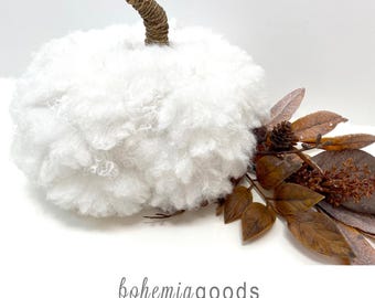May include: A white fluffy pumpkin decoration with a brown twine-wrapped stem, accented by a cluster of brown artificial leaves and a small pinecone. The text "bohemia goods" and "modern rustic + wedding supplies + florals" appears below.