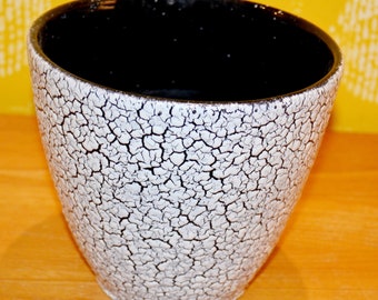 Op de afbeelding: Een witte keramische pot met een zwarte binnenkant en een gekrakelde glazuur.