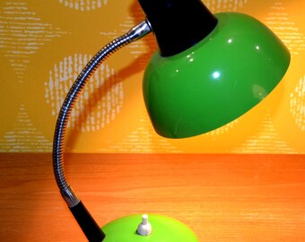 May include: A green and black desk lamp with a flexible arm and a round base. The lamp has a green shade and a black switch.