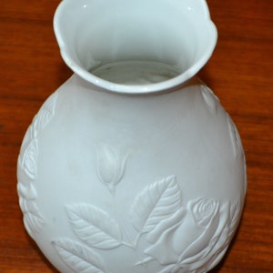 Könnte beinhalten: Weiße Porzellanvase mit einem Reliefmuster aus Rosen und Blättern.