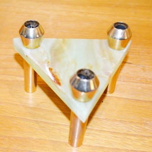 Può includere: Un portacandele triangolare in onice verde con tre coppe per candele in metallo dorato. Il portacandele ha tre gambe in metallo dorato.