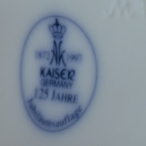 Puede incluir: Un sello de porcelana azul y blanco con una corona y el texto "1872 K 1907 Kaiser Germany 125 Jahre Jubilaums Auflage".