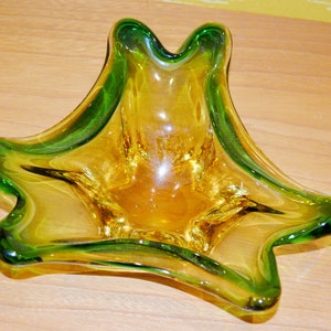 Könnte beinhalten: Eine grüne und gelbe Glasschale mit einem einzigartigen, wellenförmigen Design. Die Schale ist perfekt, um kleine Gegenstände aufzubewahren oder Snacks zu servieren.