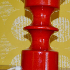 May include: A red ceramic table lamp with a white globe shade. The lamp has a unique, tiered base.