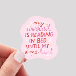May include: Pink and white sticker with the text "my workout is reading in bed until my arms hurt" with gold stars.