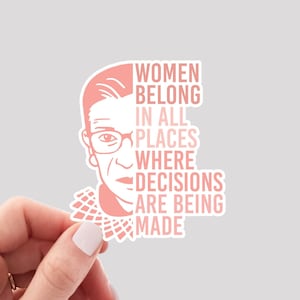 May include: Pink sticker with a silhouette of Ruth Bader Ginsburg and the text "Women belong in all places where decisions are being made."