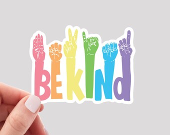 May include: A sticker with the word "BE KIND" in rainbow colors. Each letter is formed by a hand in American Sign Language.