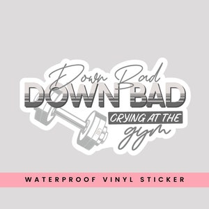 May include: A white and gray waterproof vinyl sticker with the text "Down Bad DOWN BAD Crying at the gym". The sticker features a stylized dumbbell.