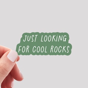 May include: A green sticker with rounded edges that says "JUST LOOKING FOR COOL ROCKS" in white text.