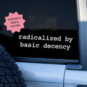 May include: A black car window with a white decal that reads "radicalized by basic decency." A pink starburst-shaped graphic in the upper left corner says "CHOOSE A SIZE & COLOR!"