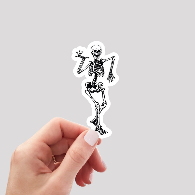 May include: A black and white sticker of a skeleton dancing. The skeleton is in a relaxed pose with one arm raised and the other at its side. The skeleton is wearing a smile.