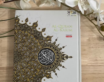 May include: A white book with a gold and black design on the cover. The title is "The Noble Quran" with the subtitle "Word-by-word Translation & Color Coded Tajweed". The book is published by Karya Bestari and is a medium size.