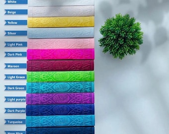 May include: A stack of colorful books in various shades including white, beige, yellow, silver, light pink, dark pink, maroon, light green, dark green, light purple, dark purple, turquoise, and navy blue. Each book has an embossed design.