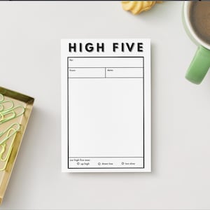 May include: A white notepad with the words "HIGH FIVE" in bold black letters. The notepad has sections for "to:", "from:", and "date:", with a space for writing. Below are options for "our high five was:" with choices "up high", "down low", and "too slow".