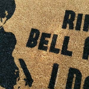 May include: A brown coir doormat with the text "Ring the bell and I'll come" in black lettering. A silhouette of a person is in the top left corner of the mat.