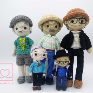 May include: Five handmade crochet dolls, each with unique outfits and accessories. The dolls feature hats, glasses, and various clothing items in shades of grey, blue, green, and brown. The dolls are standing on a white surface.