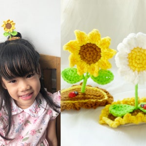 Op de afbeelding: Gehaakte zonnebloem- en madeliefjes haaraccessoires. De zonnebloem heeft gele bloemblaadjes en een bruin hart, terwijl de madeliefjes witte bloemblaadjes en een geel hart hebben. Beide bloemen hebben groene bladeren en zijn bevestigd aan een bruine basis.