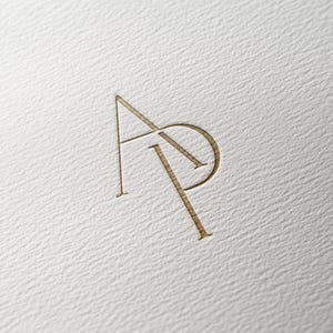May include: A gold monogram logo with the letters "AP" intertwined.