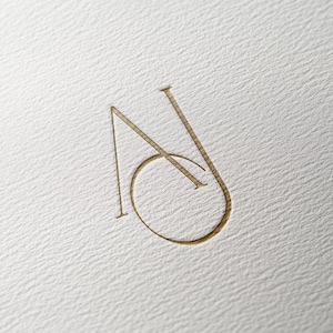 Może przedstawiać: Złote logo monogramu z literami "N" i "O" splecionymi ze sobą.