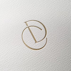 May include: A gold-colored monogram logo with the letters "CD" intertwined.