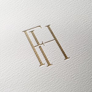 以下が含まれることがあります： セリフ体のフォントで「FH」の文字が書かれた金色のモノグラムです。
