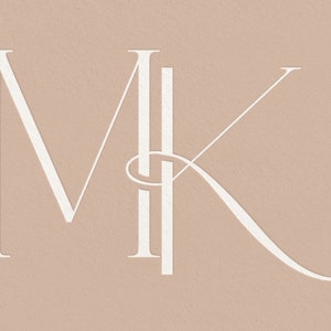Op de afbeelding: Witte monogram-initialen "MK" in een modern, elegant lettertype op een lichtbruine achtergrond.