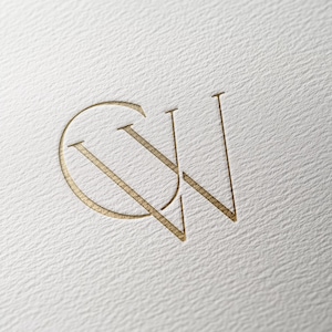 May include: Gold-colored monogram logo featuring the letters "CW" intertwined. The "C" is a rounded shape, and the "W" is formed by two diagonal lines. The logo is embossed on a textured, off-white paper surface.