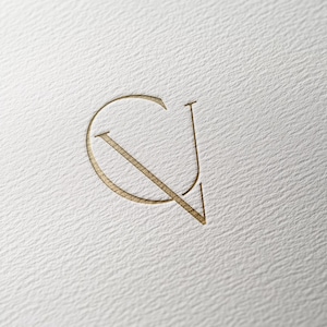 May include: A gold-colored monogram logo with the letters "C" and "V" intertwined.
